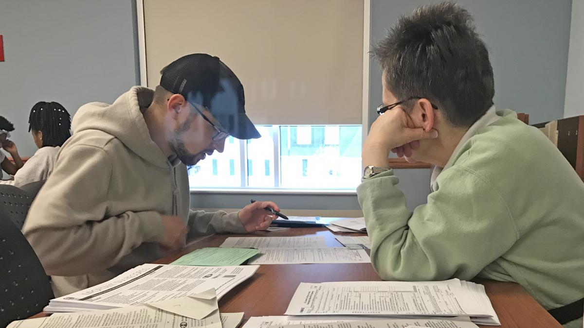 Volunteer and taxpay, seated at table, working on taxes