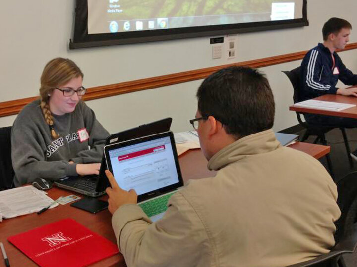 Volunteers seated across from each other at table, with laptops