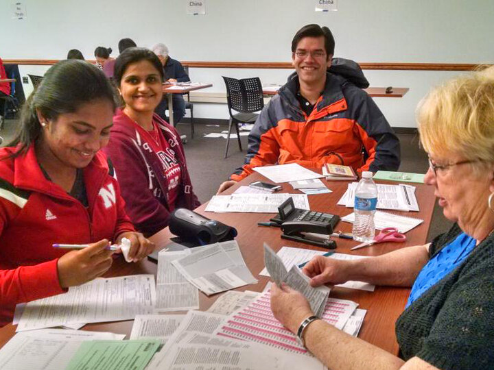 Volunteers sitting at table, across from taxpayer