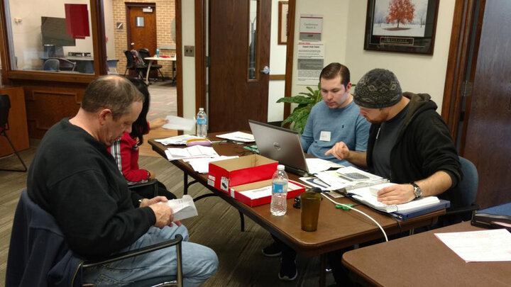 Volunteers sitting across table from taxpayer, assisting with taxes